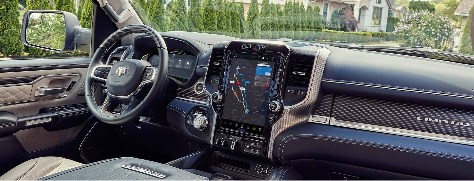 The interior of the 2023 Ram 1500 Limited Elite, showing the steering wheel and touchscreen, which is displaying a map of the vehicle's surroundings.