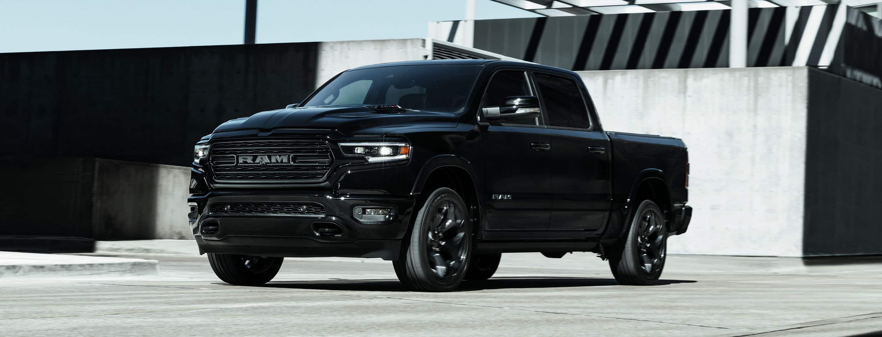 A black 2023 Ram 1500 Limited Night Edition Crew Cab parked near a contemporary building.