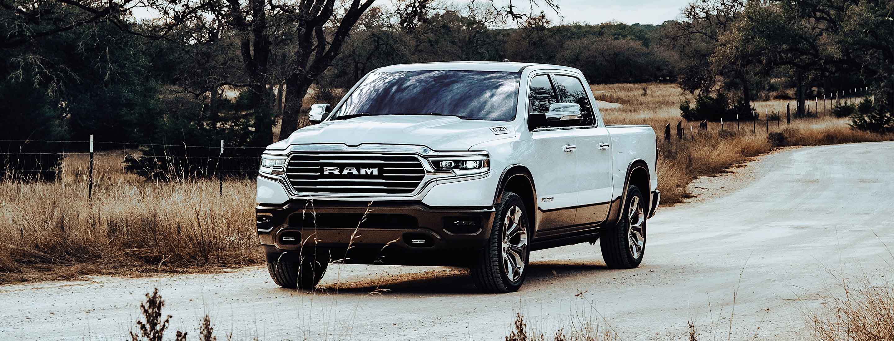 A white 2023 Ram 1500 Limited Longhorn Southfork Edition being driven on a country road.