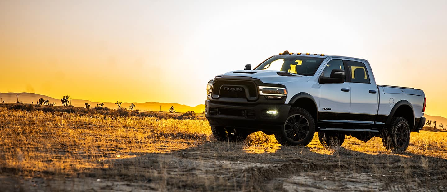 A 2023 Ram 2500 Rebel parked on a grassy clearing at sunrise.
