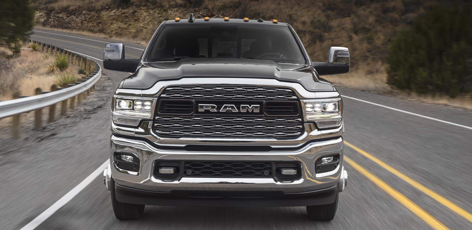 Display A head-on view of a 2023 Ram 3500 Limited being driven on a winding highway.