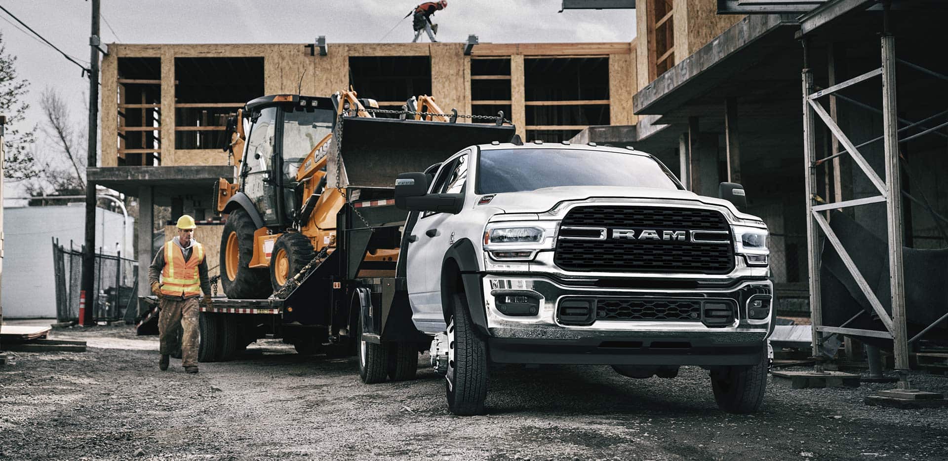 Display The 2023 Ram Chassis Cab Crew Cab on a construction site with an excavator in tow.