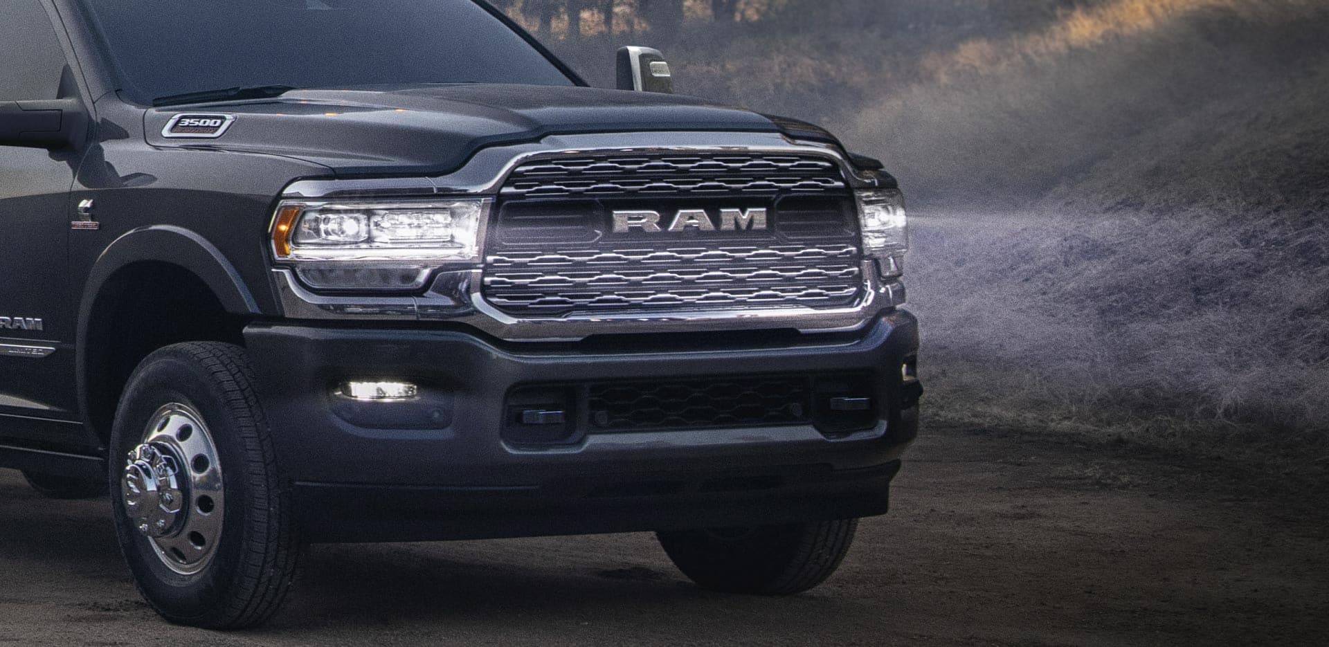 Display The front end of a 2023 Ram 3500 Chassis Cab with its LED headlamps on, illuminating the road ahead.