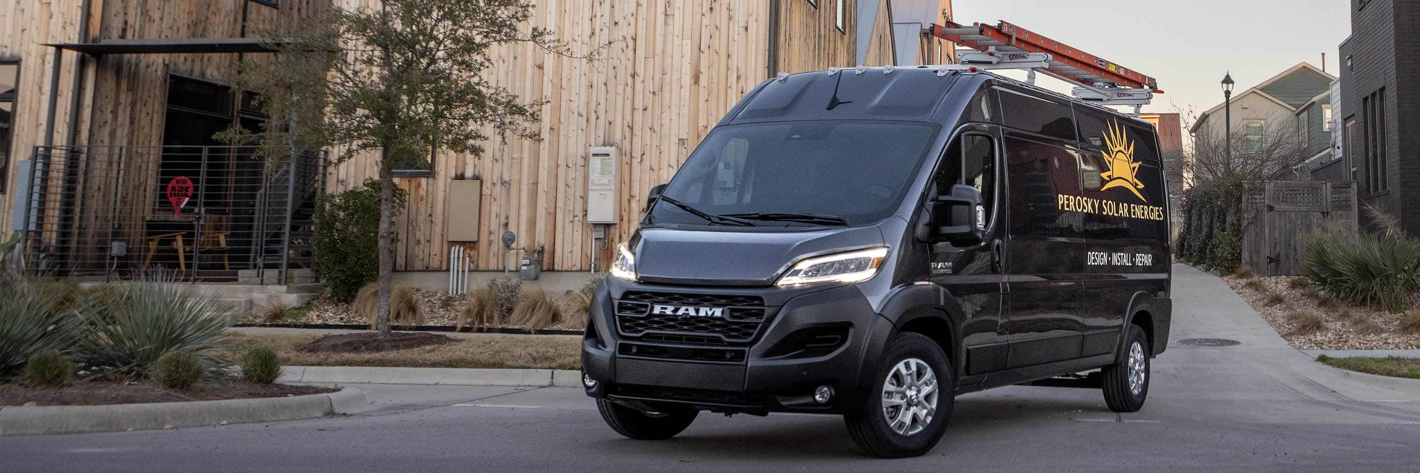 The 2023 Ram ProMaster 2500 Cargo Van with a ladder on its roof rack and the logo for a solar energy company on its side.