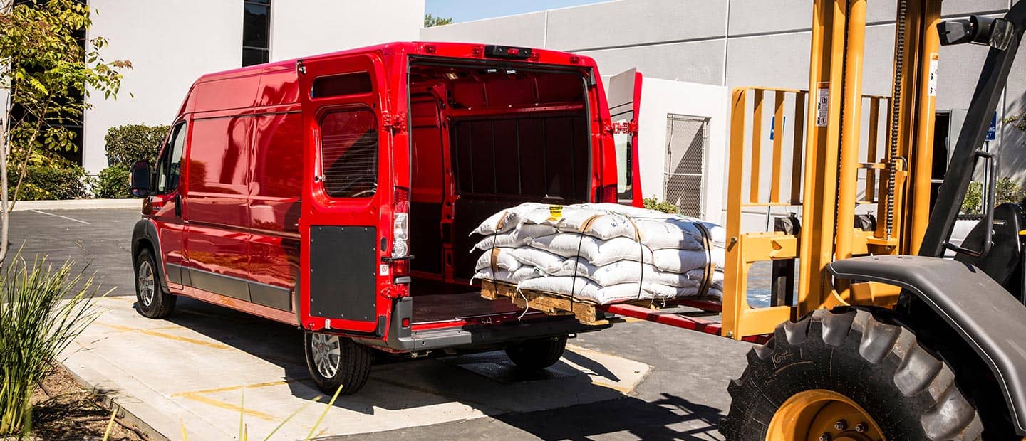 A forklift loading a pallet stacked with sacks into the rear of a 2023 Ram ProMaster 2500 Cargo Van.