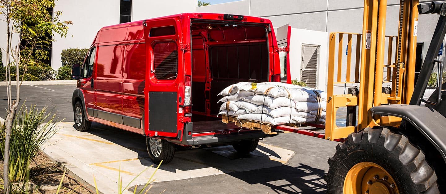 A forklift loading a pallet stacked with sacks through the rear doors of the 2023 Ram ProMaster 2500 Cargo Van.