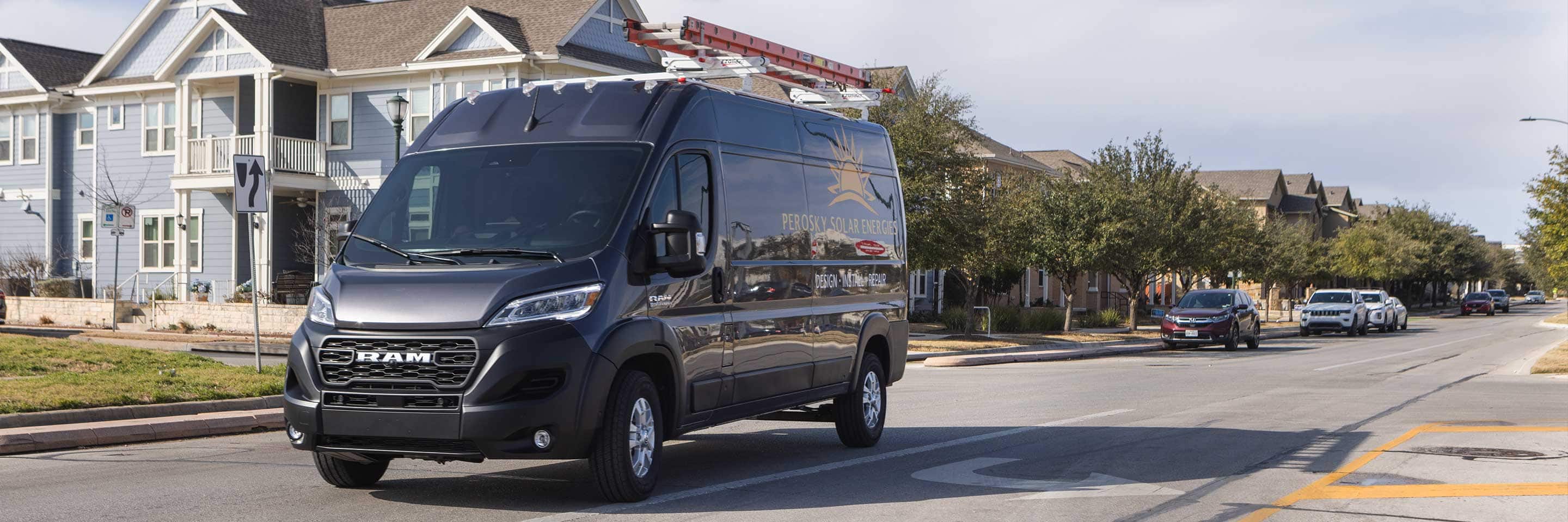 The 2023 Ram ProMaster 2500 Cargo Van High Roof with a ladder attached to its roof rack, parked in a residential neighborhood.