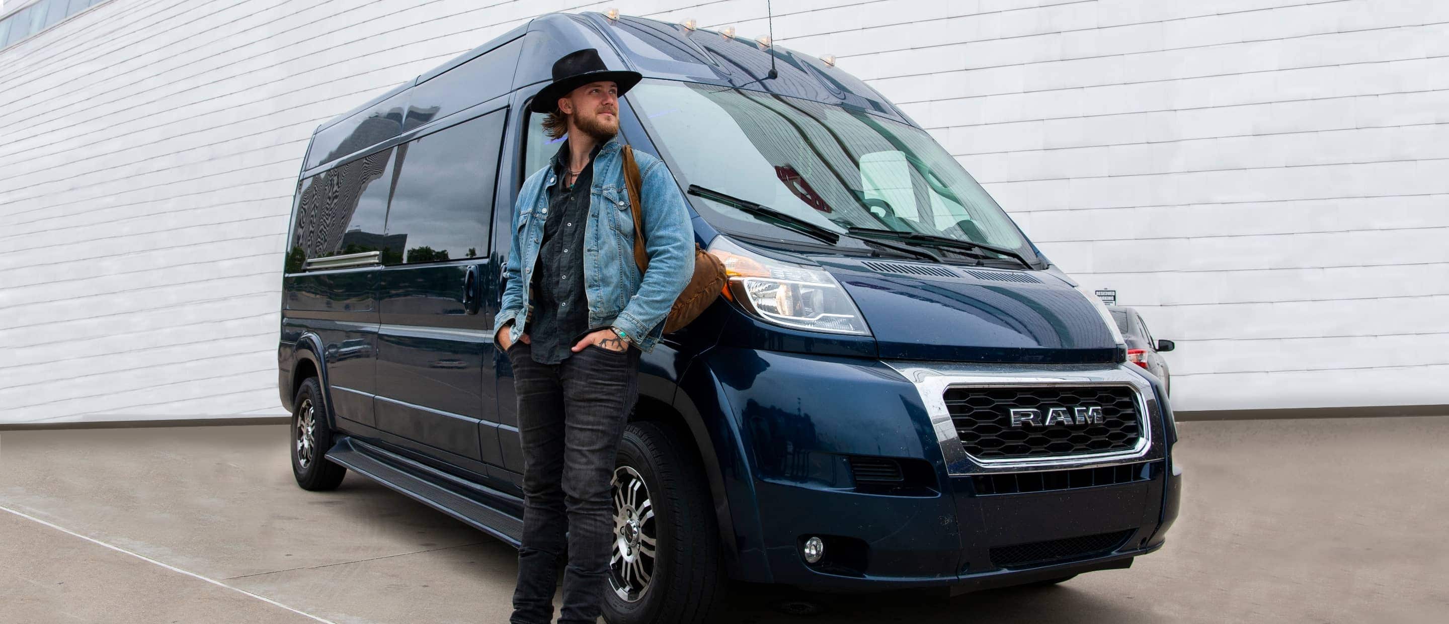 Country artist Jackson Dean standing beside the 2023 Ram ProMaster BandVan—a Ram ProMaster 2500 High Roof Window Van with aftermarket accessories.