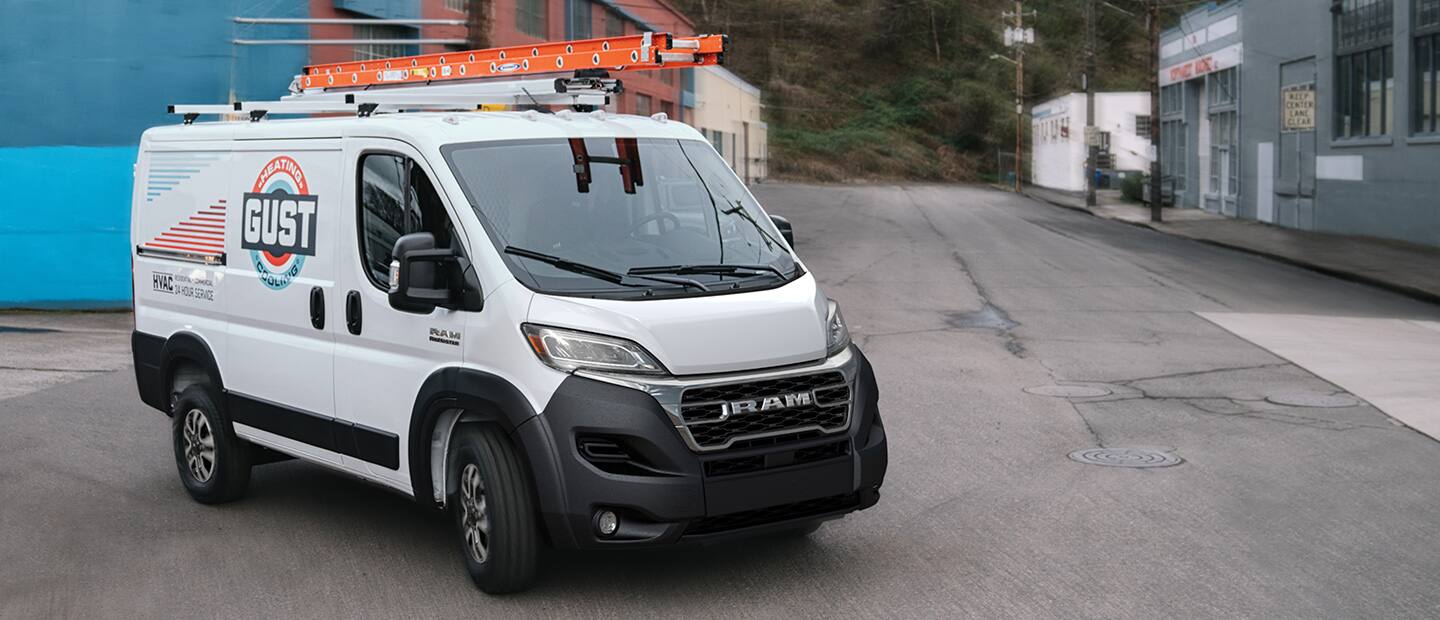A 2023 Ram ProMaster 1500 Cargo Van with two ladders on its roof rack and an HVAC company logo on its side.