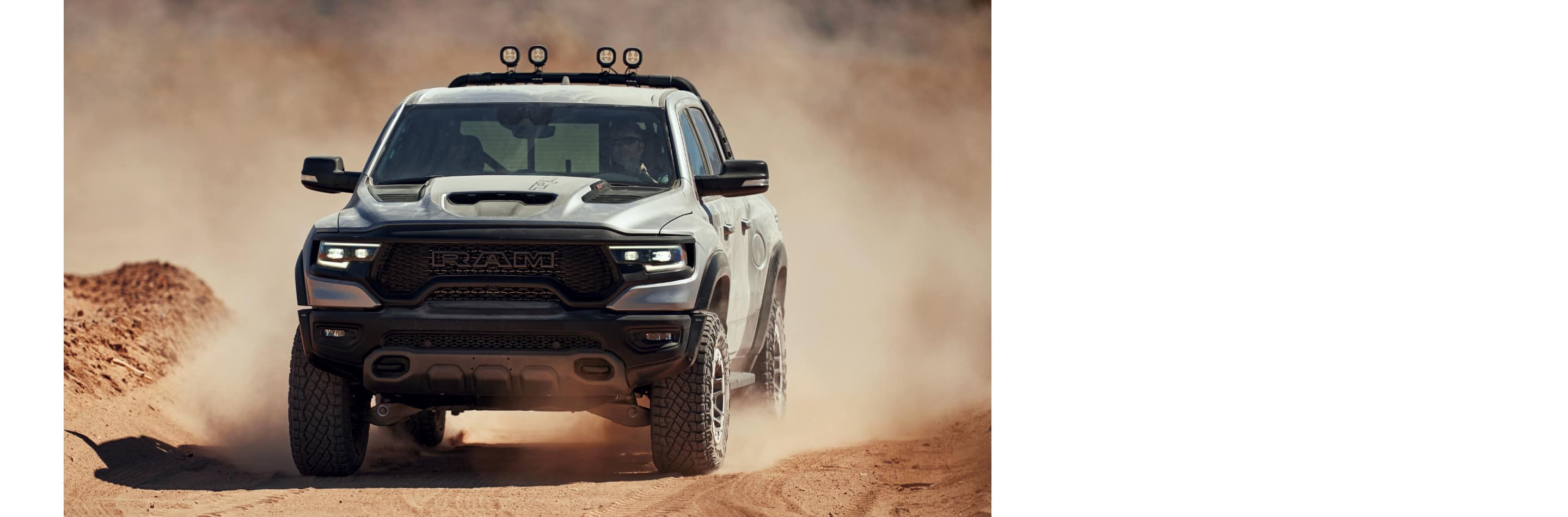 A silver 2024 Ram 1500 TRX Crew Cab being driven off-road, on a trail through the desert.