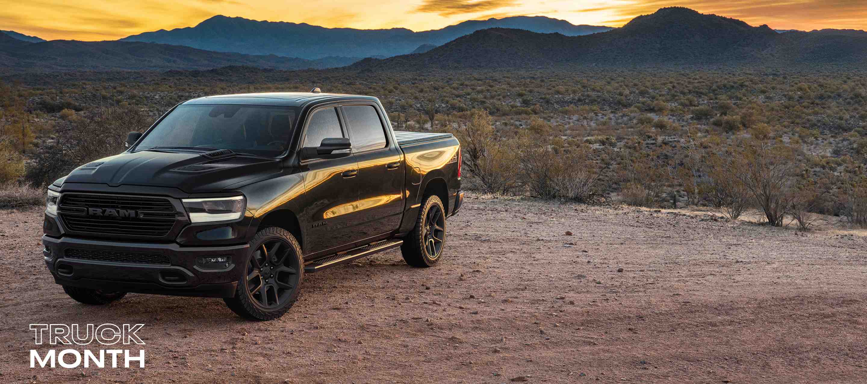 A black 2024 Ram 1500 Laramie Crew Cab in the desert. Truck Month Sales Event.