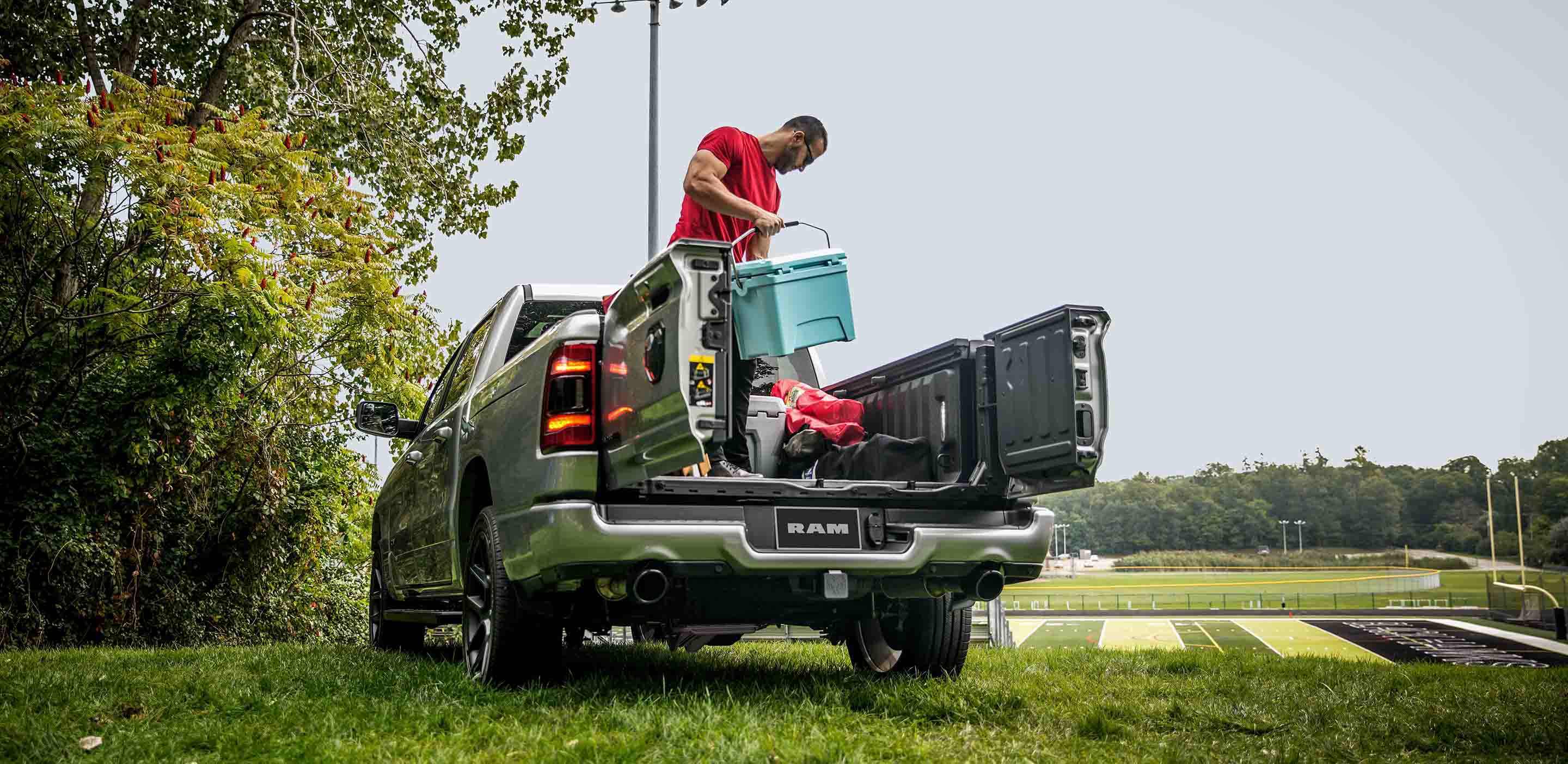  Man loading cooler in the bed of the Ram 1500 Laramie with tailgate French doors open