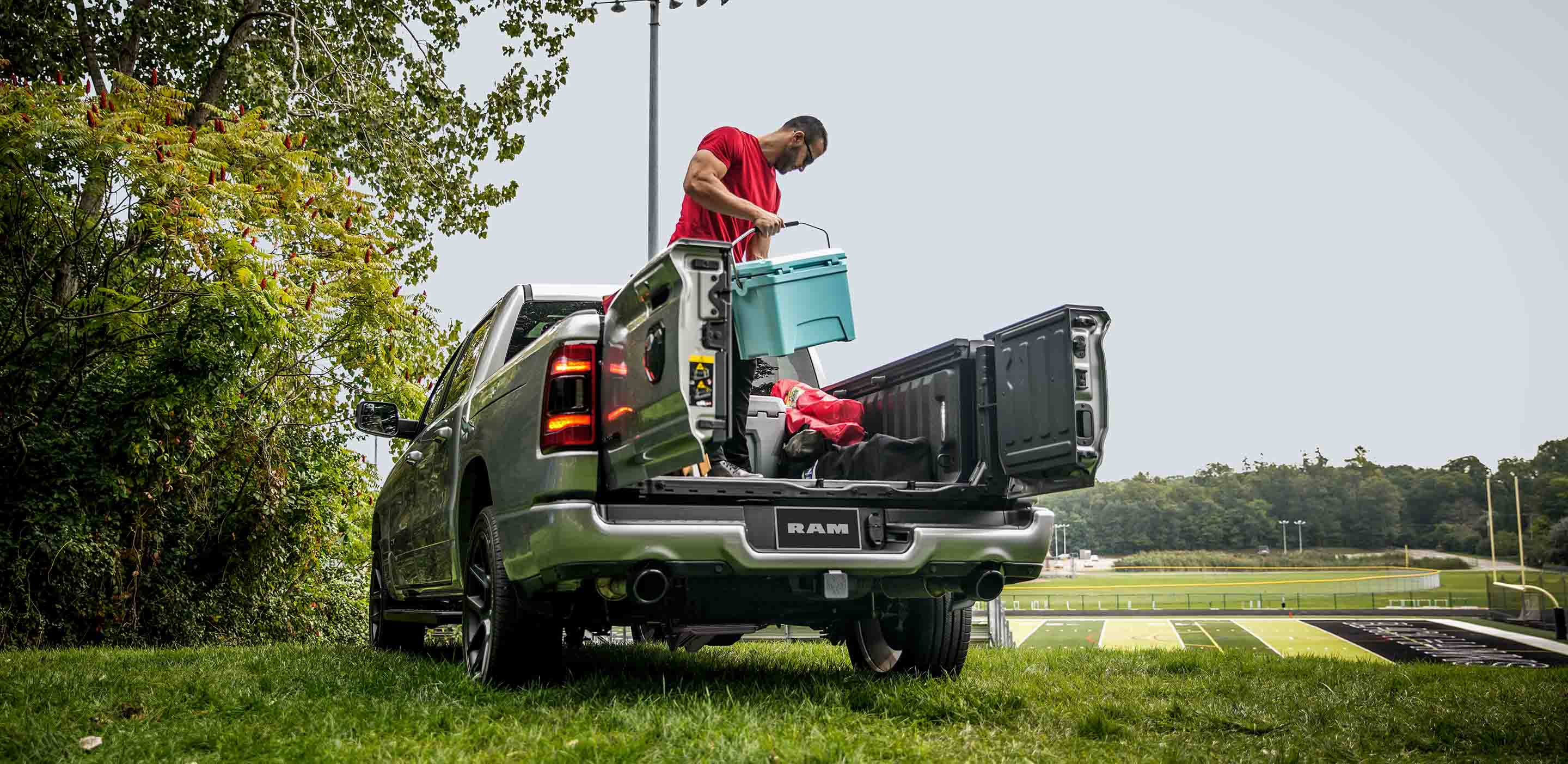 Man loading cooler in the bed of the Ram 1500 Laramie with tailgate French doors open