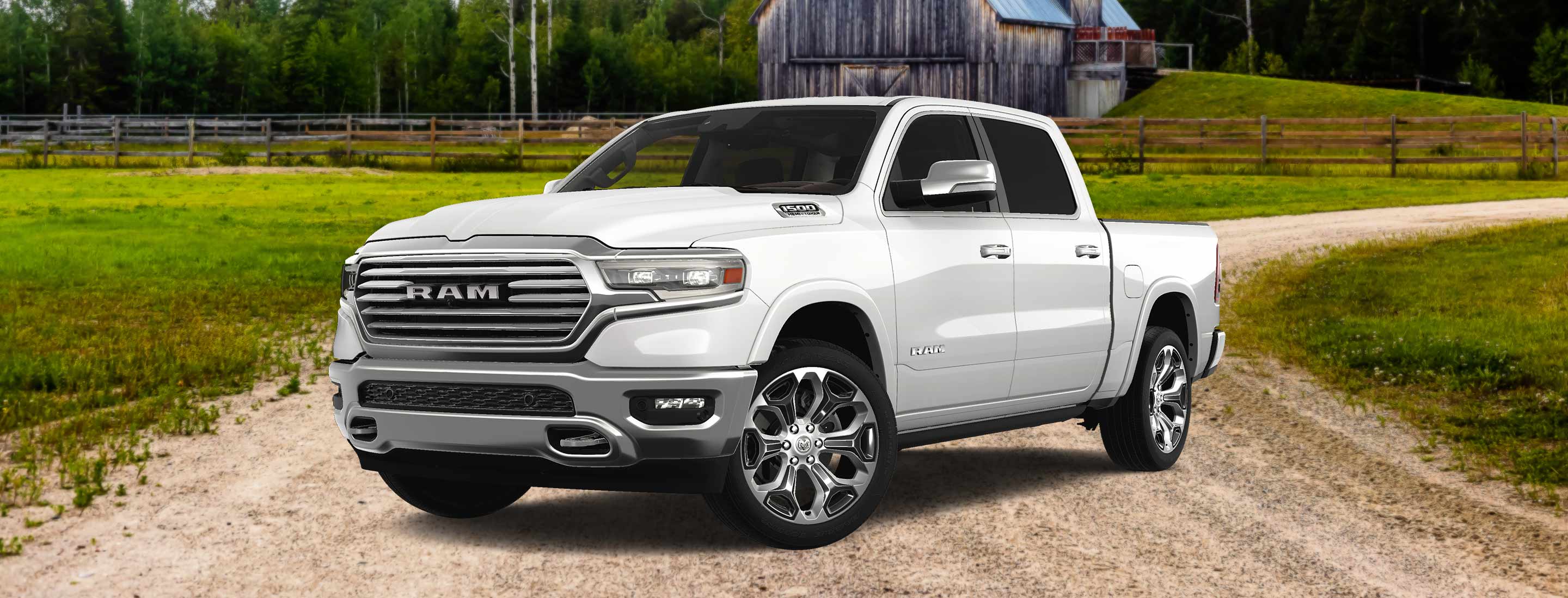 An angled front driver-side profile of a white 2024 Ram 1500 Limited Longhorn Southfork Edition Crew Cab parked at a farm.