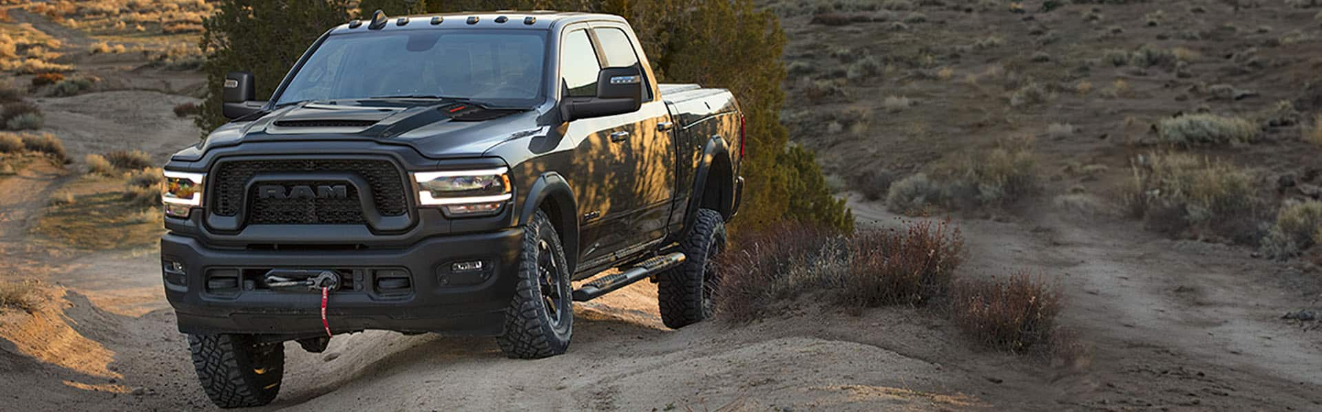 A 2024 Ram 2500 Power Wagon Crew Cab being driven off-road with its axles articulating to keep its wheels on the ground over an uneven surface.