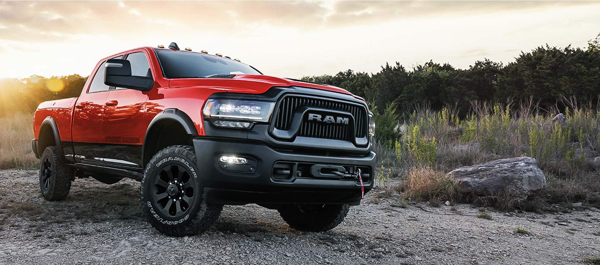 An angled passenger-side front profile of a red 2024 Ram 2500 Power Wagon parked on a trail off-road.