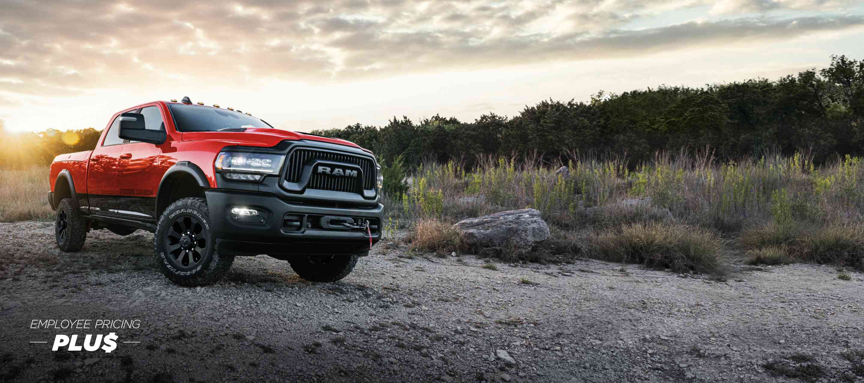 A red 2024 Ram 2500 Power Wagon 4x4 Crew Cab parked on a clearing, off-road at sunset. Employee Pricing Plus Sales Event.