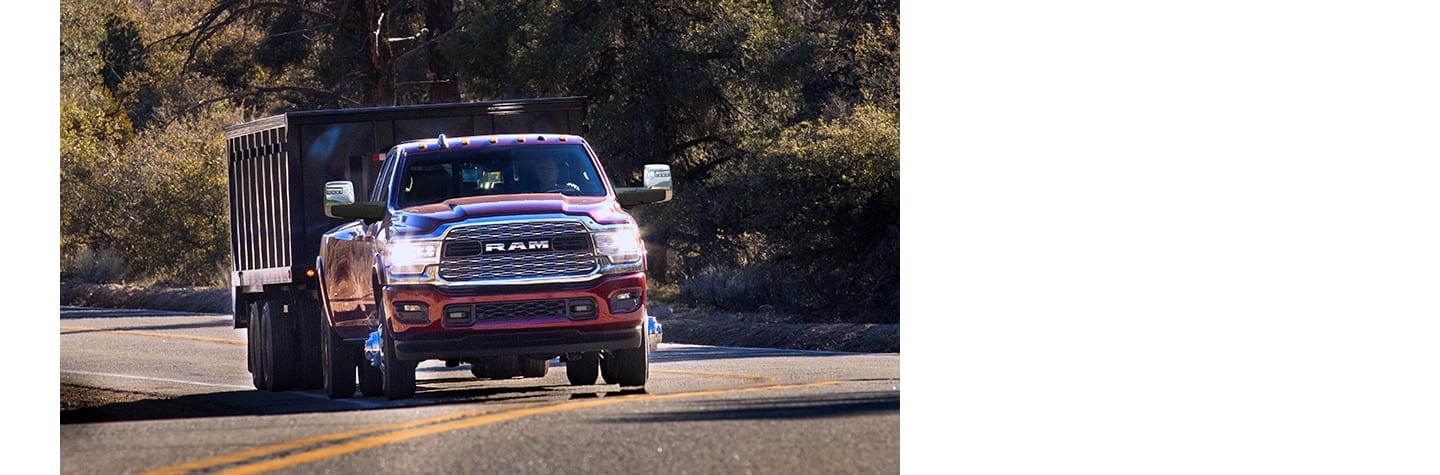 A red 2024 Ram 3500 Limited 4x4 Crew Cab towing an enclosed box.