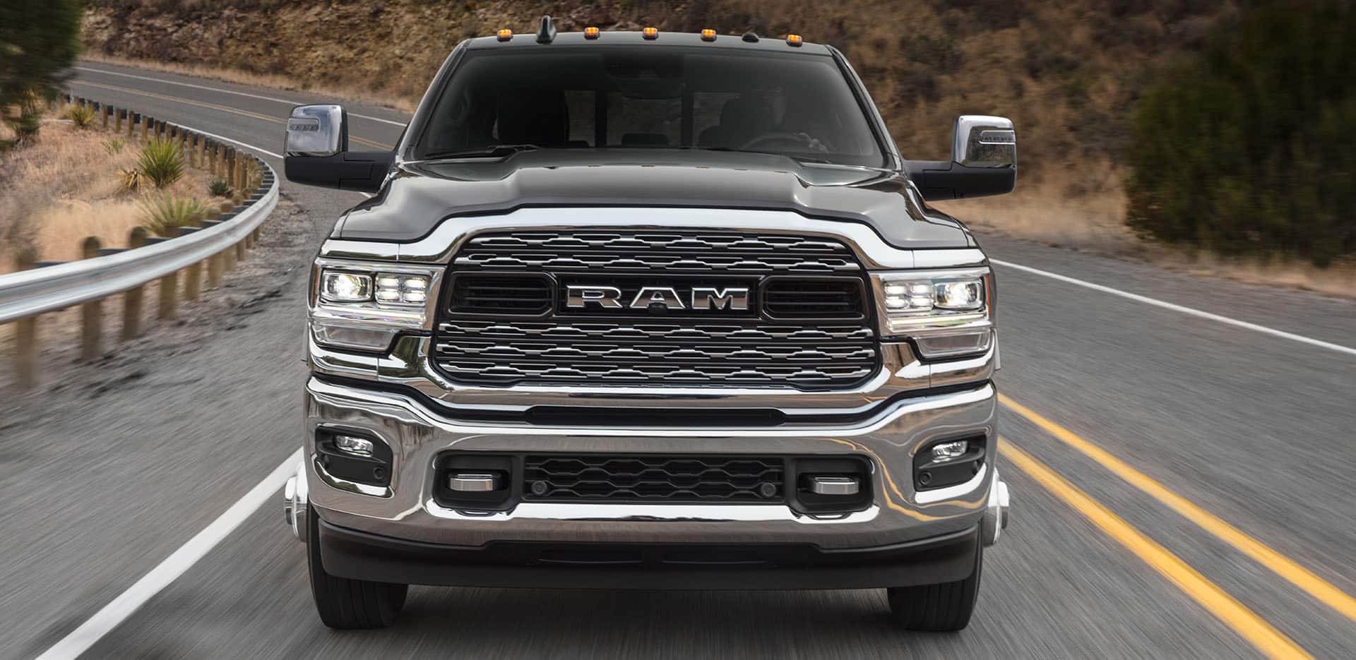 Display A head-on angle of a gray 2024 Ram 3500 Limited being driven on a winding highway.