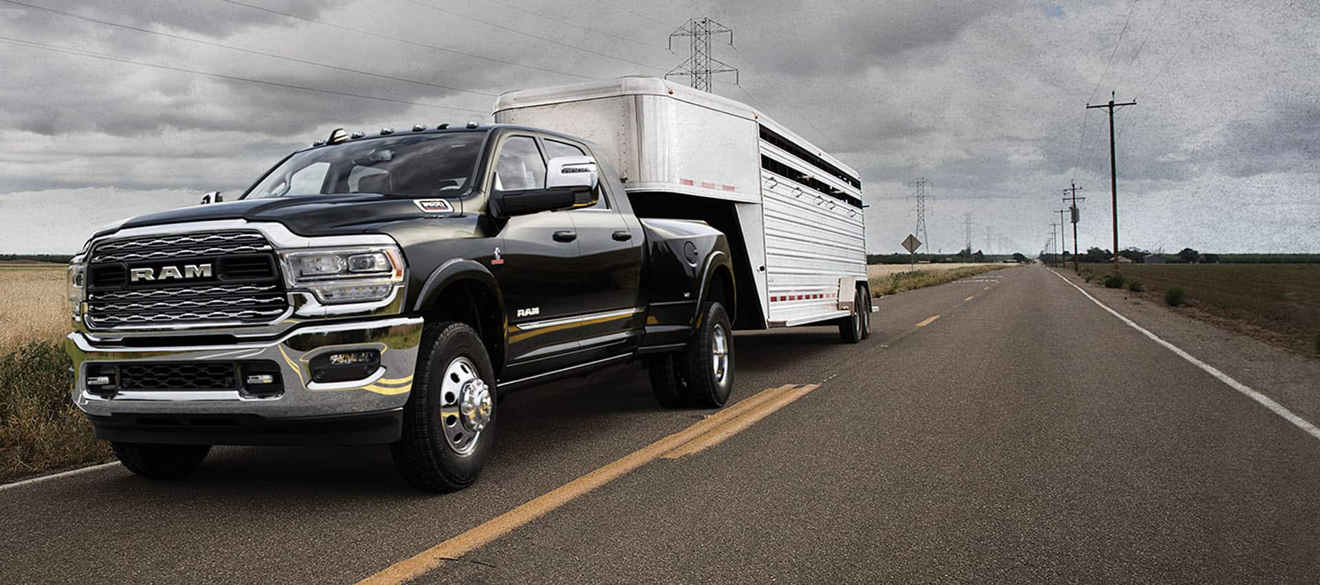 A black 2024 Ram 3500 Limited Crew Cab towing a fifth wheel travel trailer as it is driven down the highway.