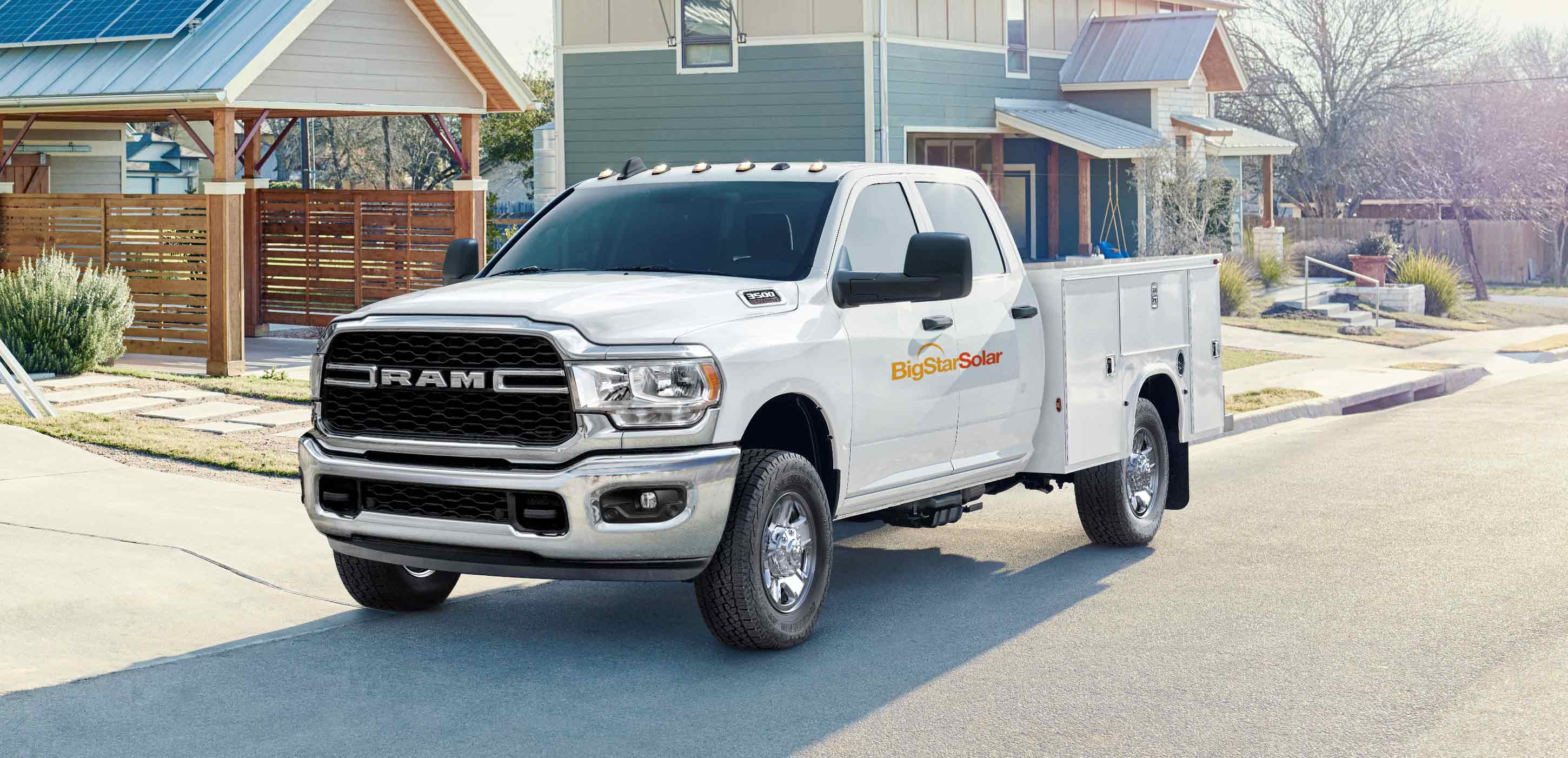 Display A white 2024 Ram 3500 Tradesman Chassis Cab Crew Cab with a solar company logo on its side, parked in front of a home with solar panels on the garage roof.