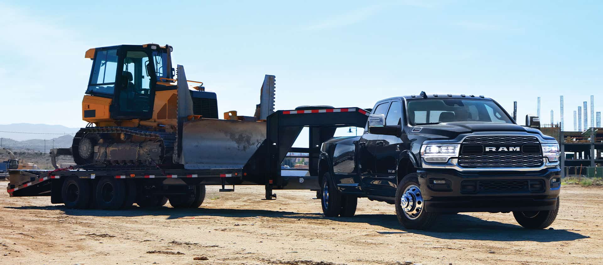 A black 2024 Ram 3500 Limited Crew Cab towing a fifth wheel flatbed trailer with an excavator on it.
