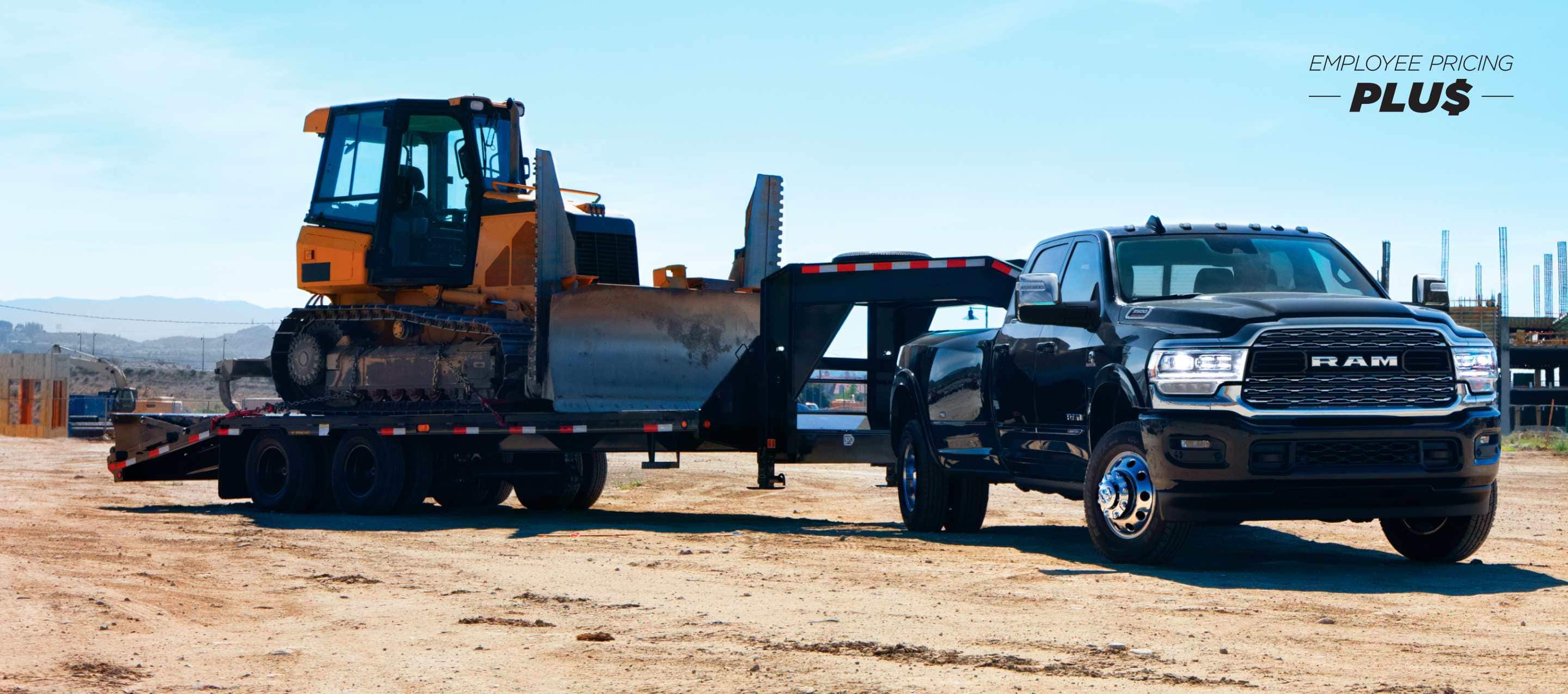 A black 2024 Ram 3500 Limited Crew Cab towing a fifth wheel flatbed trailer with an excavator on it. Employee Pricing Plus Sales Event.