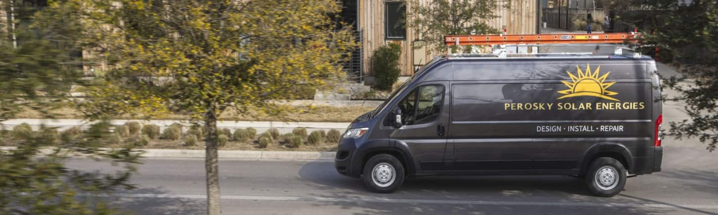 A driver-side profile of a gray 2024 Ram ProMaster 2500 Tradesman Cargo Van High Roof with a ladder attached to its roof rack and signage for a solar company on its side panel.