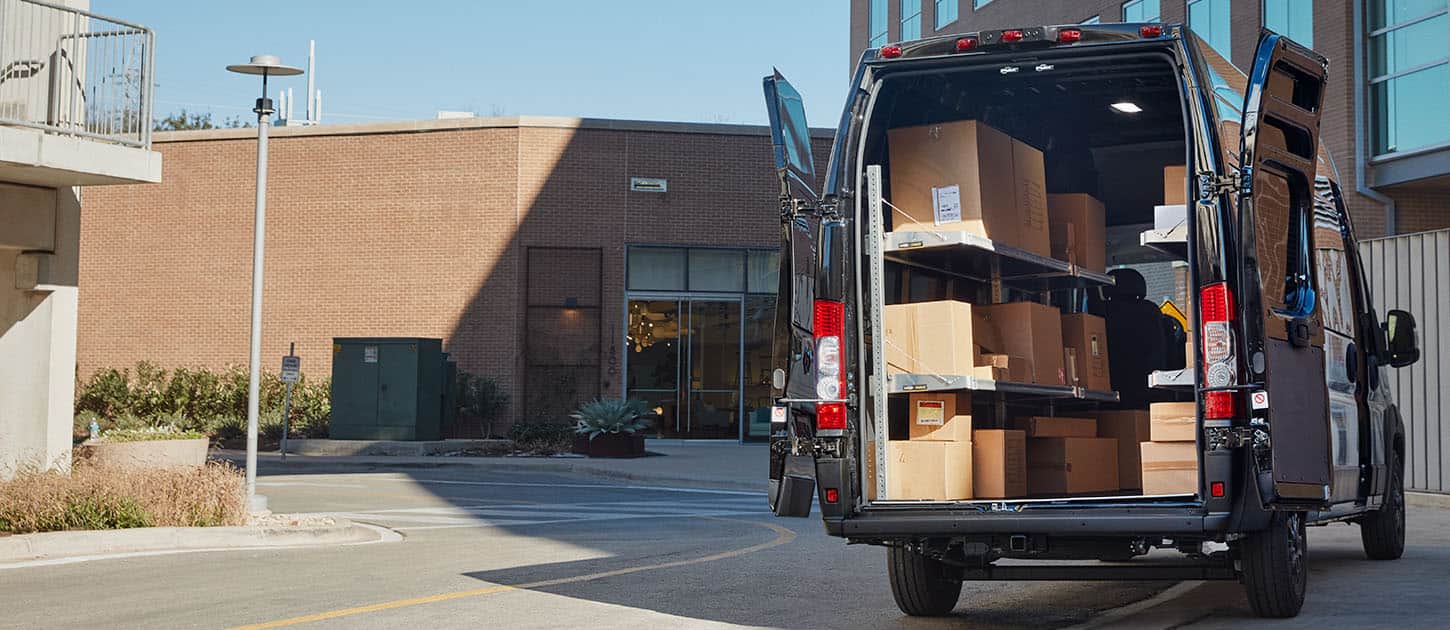 A rear angle of the 2024 Ram ProMaster 3500 SLT+ Cargo Van Super High Roof with its rear doors fully open and the cargo area full of boxes.