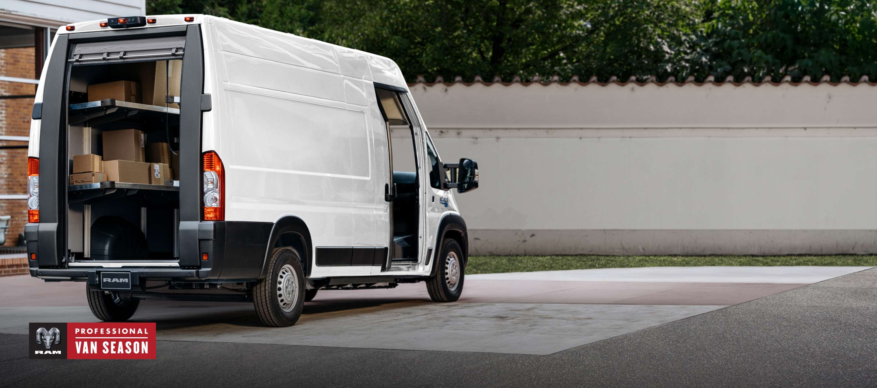 A rear passenger-side angle of a white 2024 Ram ProMaster EV Step Van Super High Roof with its rear roll-up door raised and passenger sliding pocket door open. Professional Van Season.