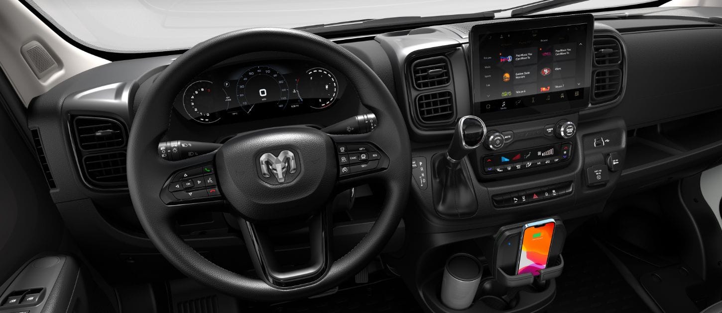 The steering wheel, Driver Information Digital Cluster, Uconnect touchscreen, center stack controls and wireless charging pad in the 2024 Ram ProMaster.