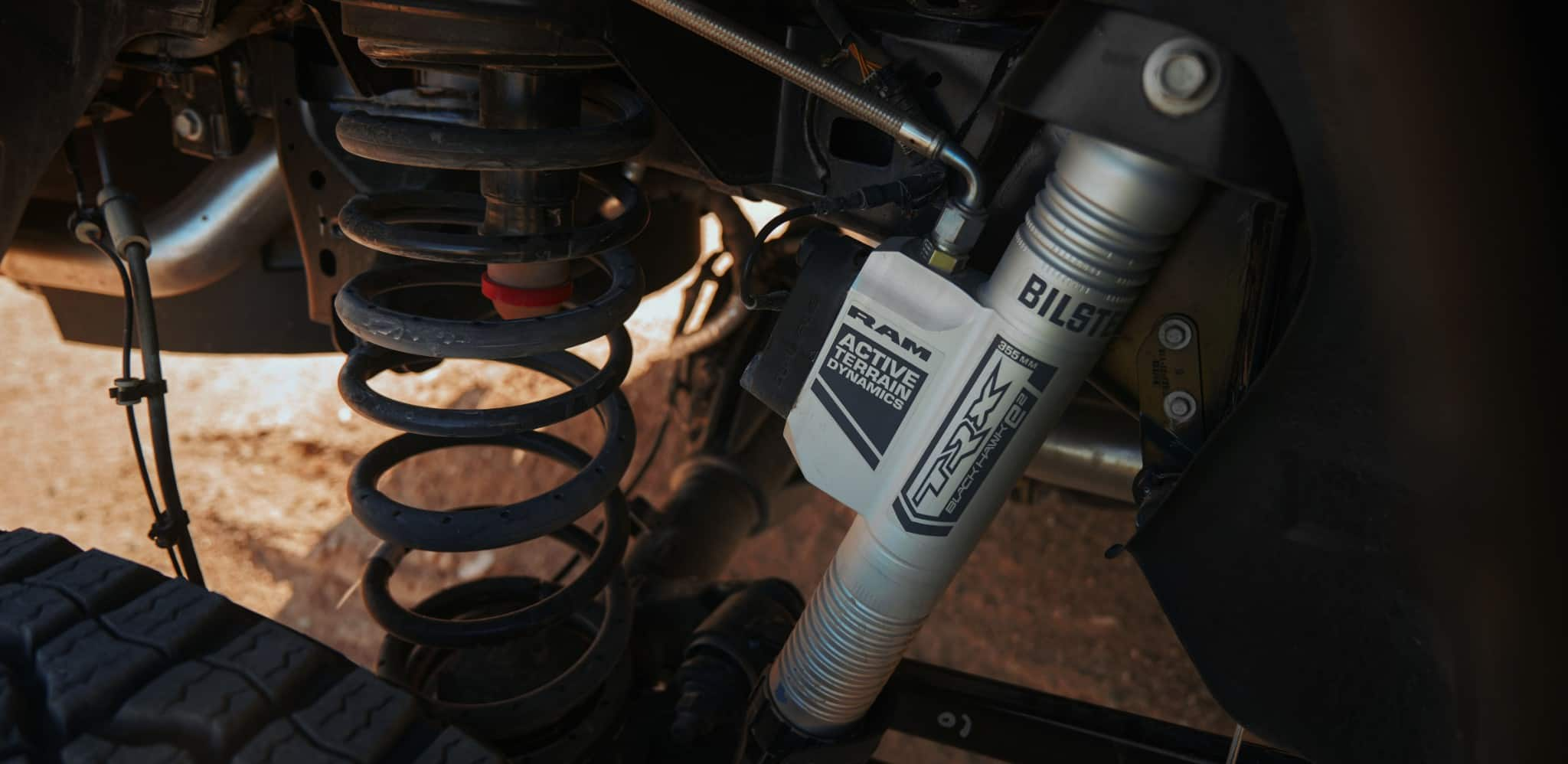 Display An undercarriage angle displaying a close-up of the Bilstein black hawk e2 shock system on the 2024 Ram 1500 TRX.