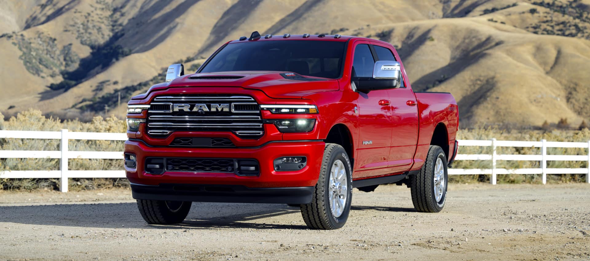 A red 2025 Ram 2500 Laramie 4x4 Crew Cab parked at a ranch in the desert.