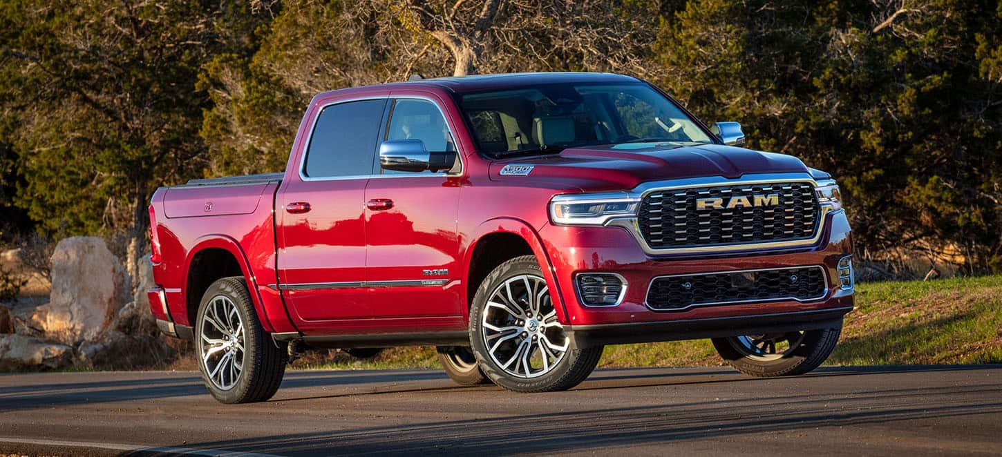 A red 2025 Ram 1500 Tungsten Crew Cab being driven on a highway.