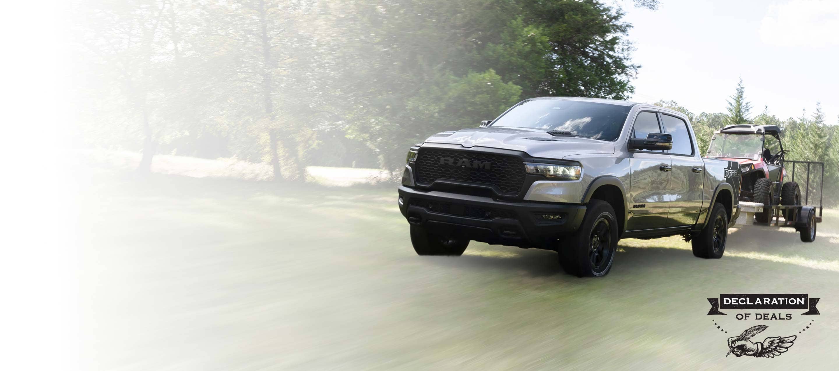 A gray 2025 Ram 1500 Rebel 4x4 Crew Cab towing an ATV on a utility trailer. Declaration of Deals Sales Event.