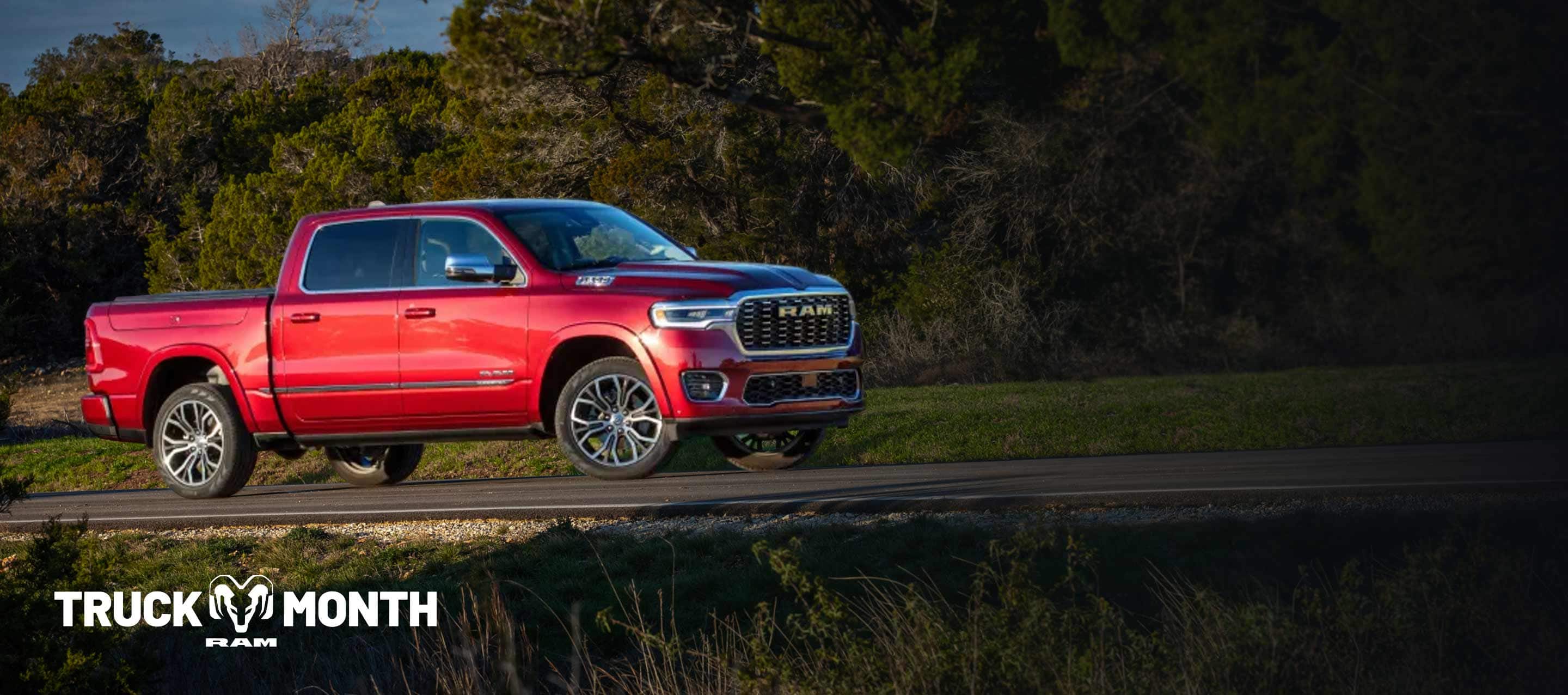 A red 2025 Ram 1500 Tungsten 4x4 Crew Cab traveling on a country road. Truck Of The Month Sales Event.