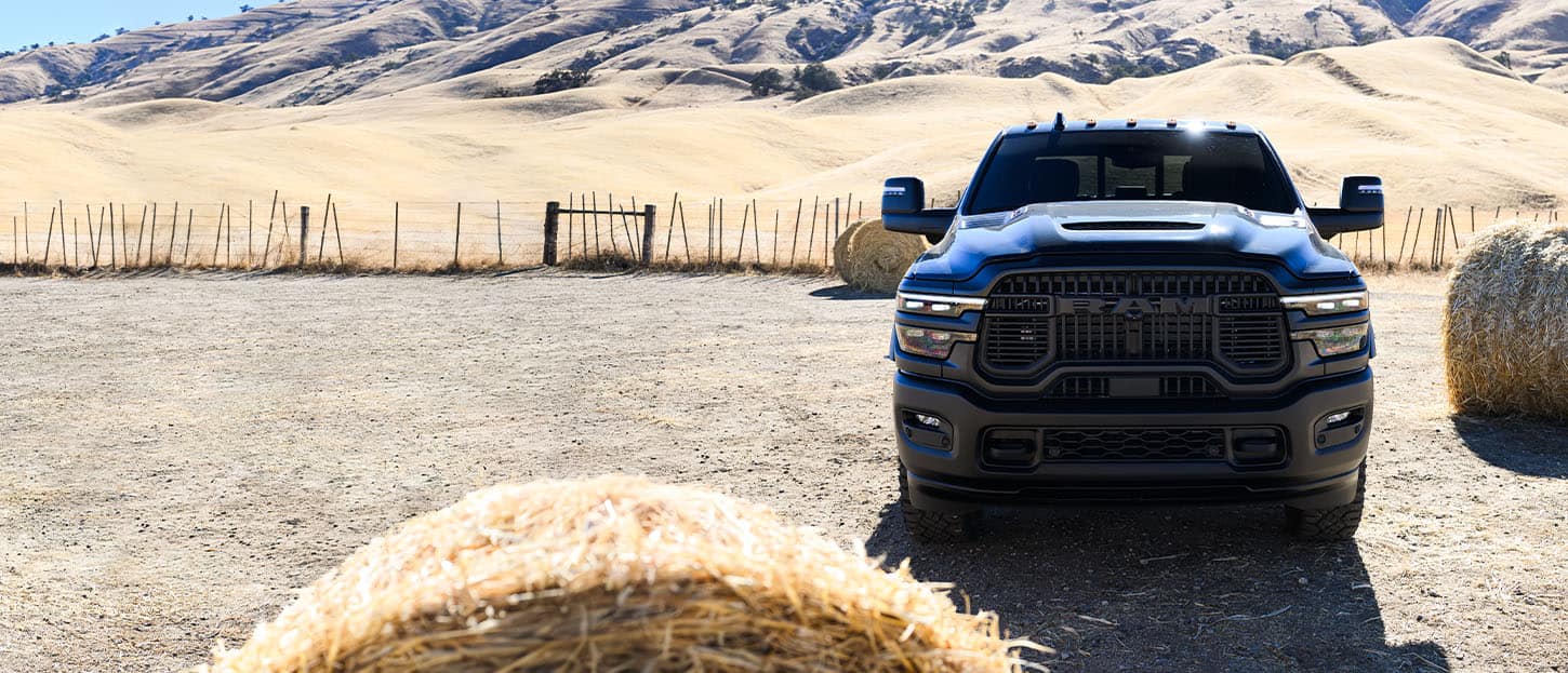 A head-on angle of a blue 2025 Ram 2500 Rebel 4x4 parked at a ranch.