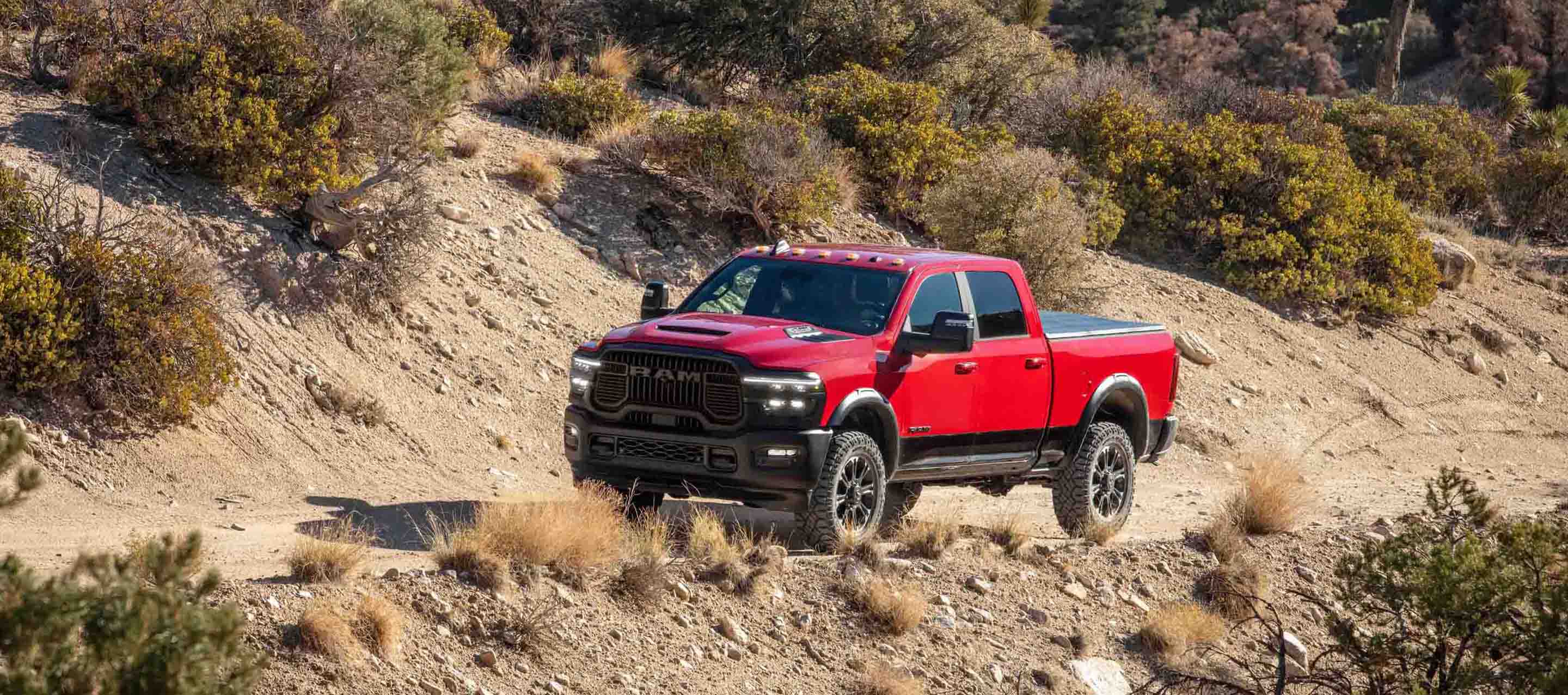 A red 2025 Ram 2500 Laramie 4x4 Crew Cab traveling on a trail off-road.