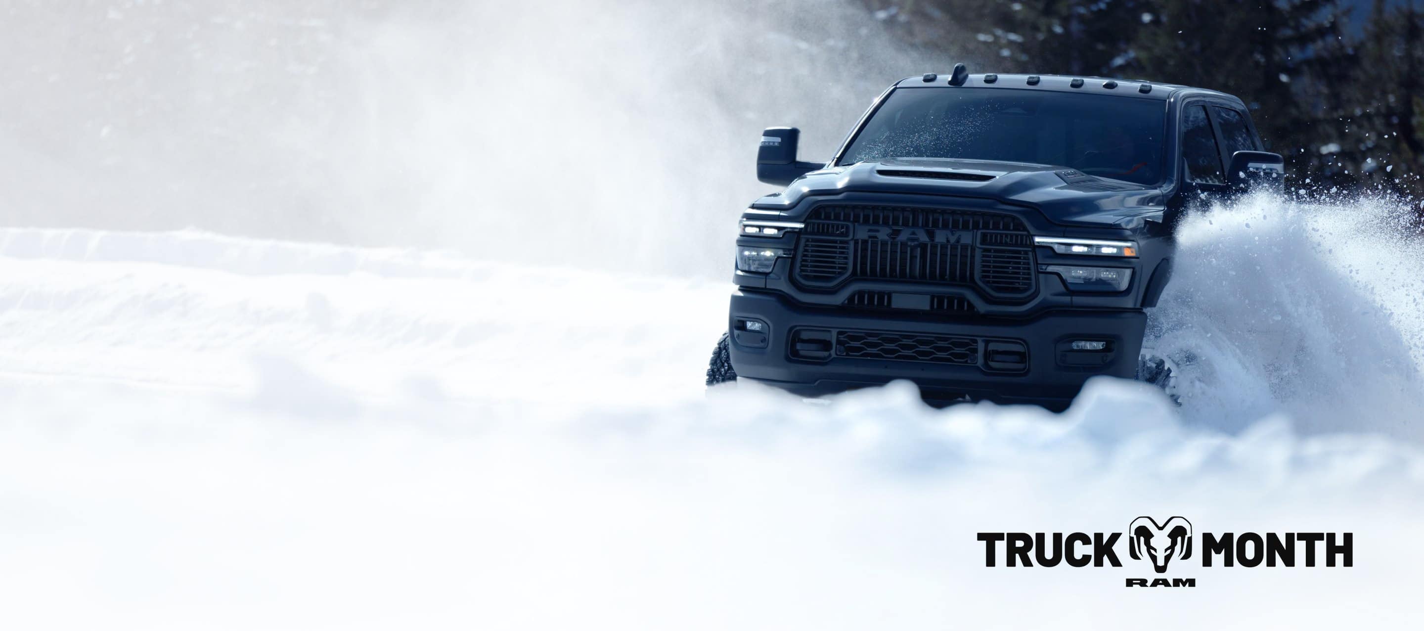 A gray 2025 Ram 2500 Rebel 4x4 Crew Cab traveling through deep snow in a forest. Truck of The Month Sales Event.