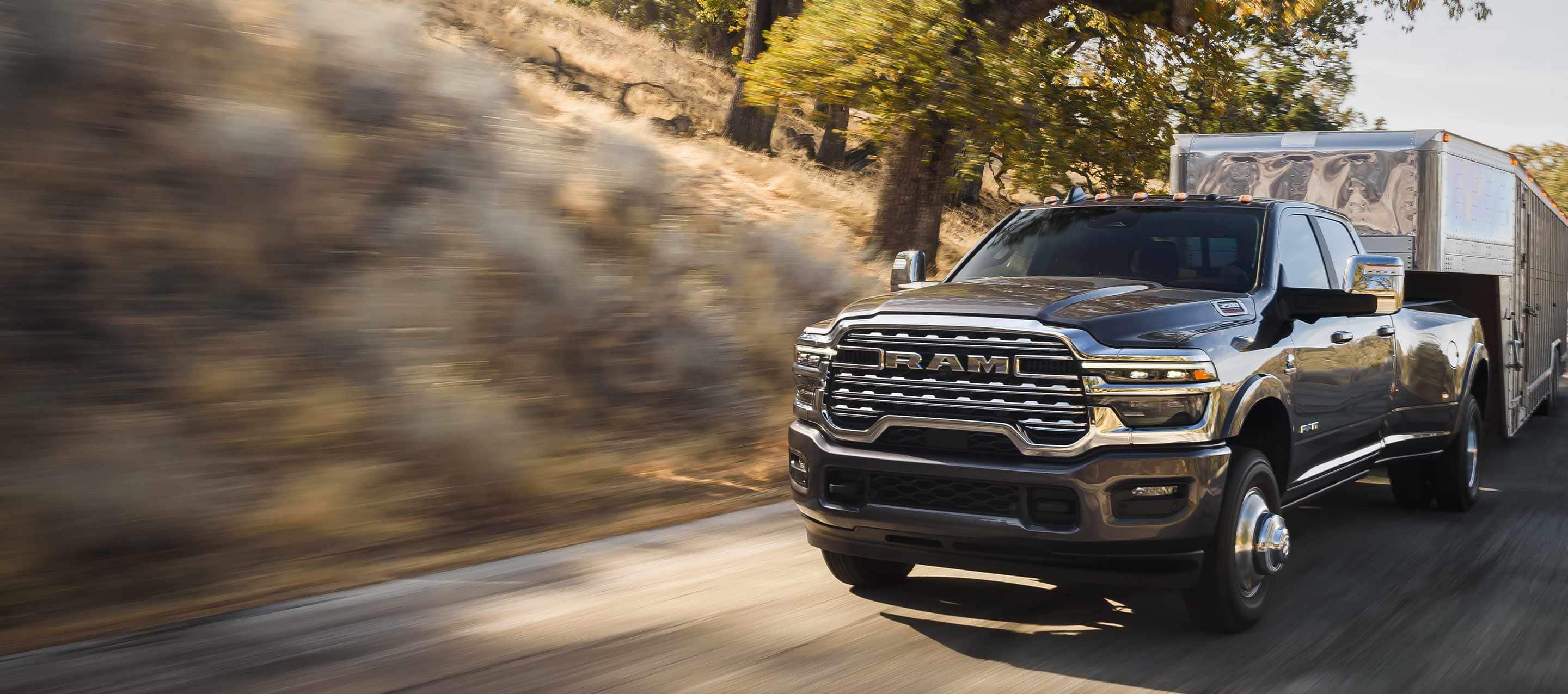 A gray 2025 Ram 3500 Limited Longhorn 4x4 Crew Cab towing a large fifth-wheel livestock trailer.