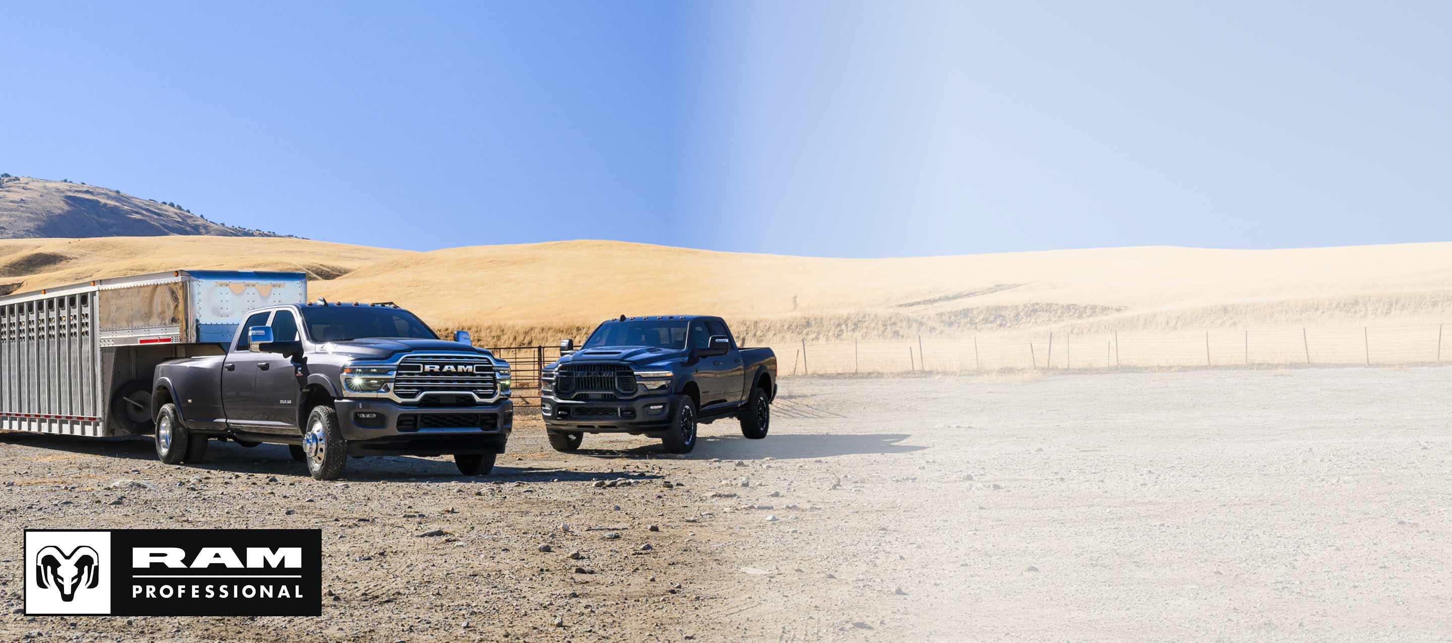 A gray 2025 Ram 3500 Heavy Duty Limited Longhorn 4x4 Crew Cab towing a large fifth-wheel livestock trailer at a ranch, with a black Ram 2500 Rebel parked nearby. Ram Professional.