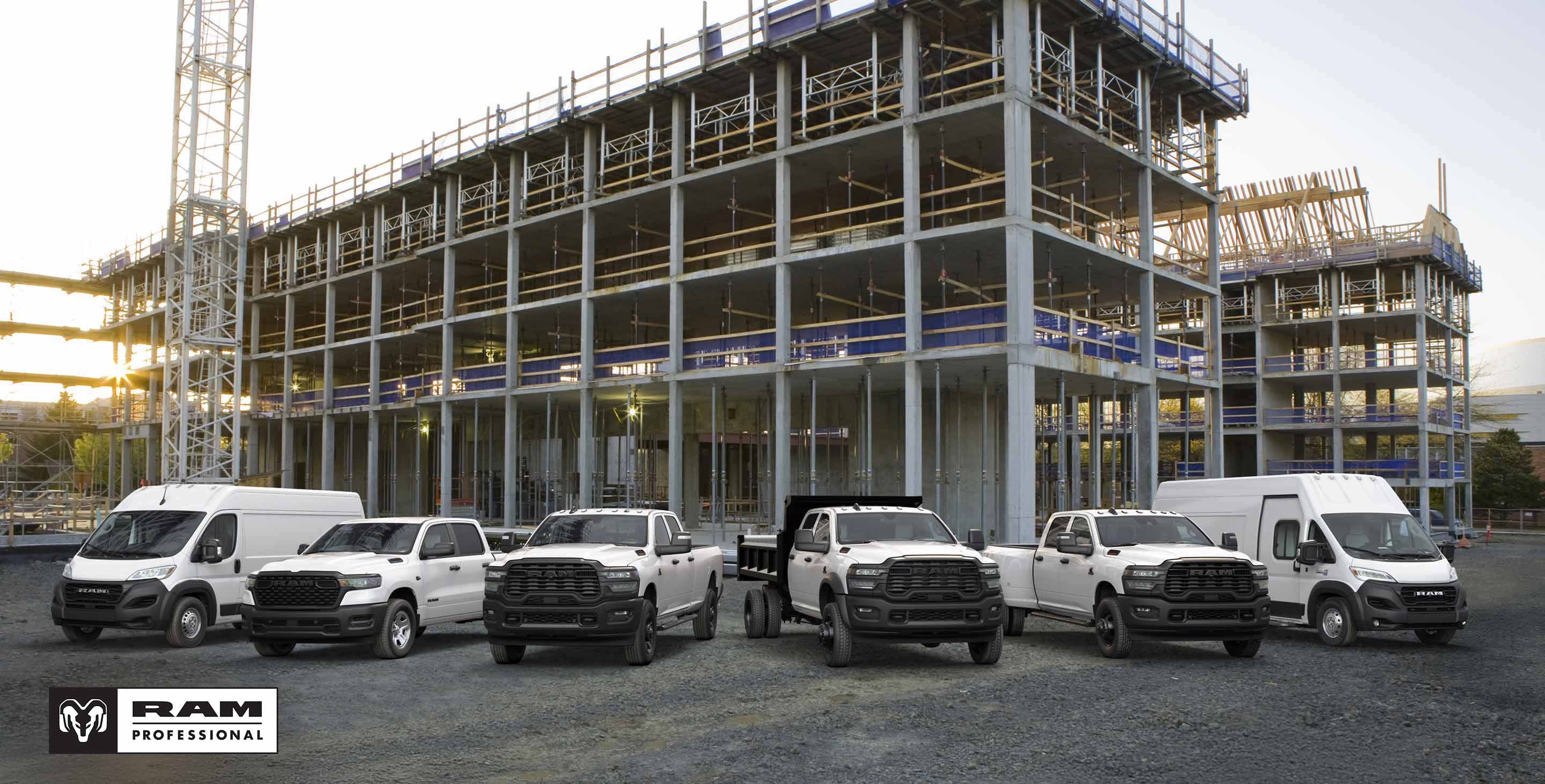 A passenger-side front angle of a white 2025 Ram ProMaster 1500 Tradesman Standard Roof Cargo Van parked at a building site with a ladder on its roof rack. Ram Professional.