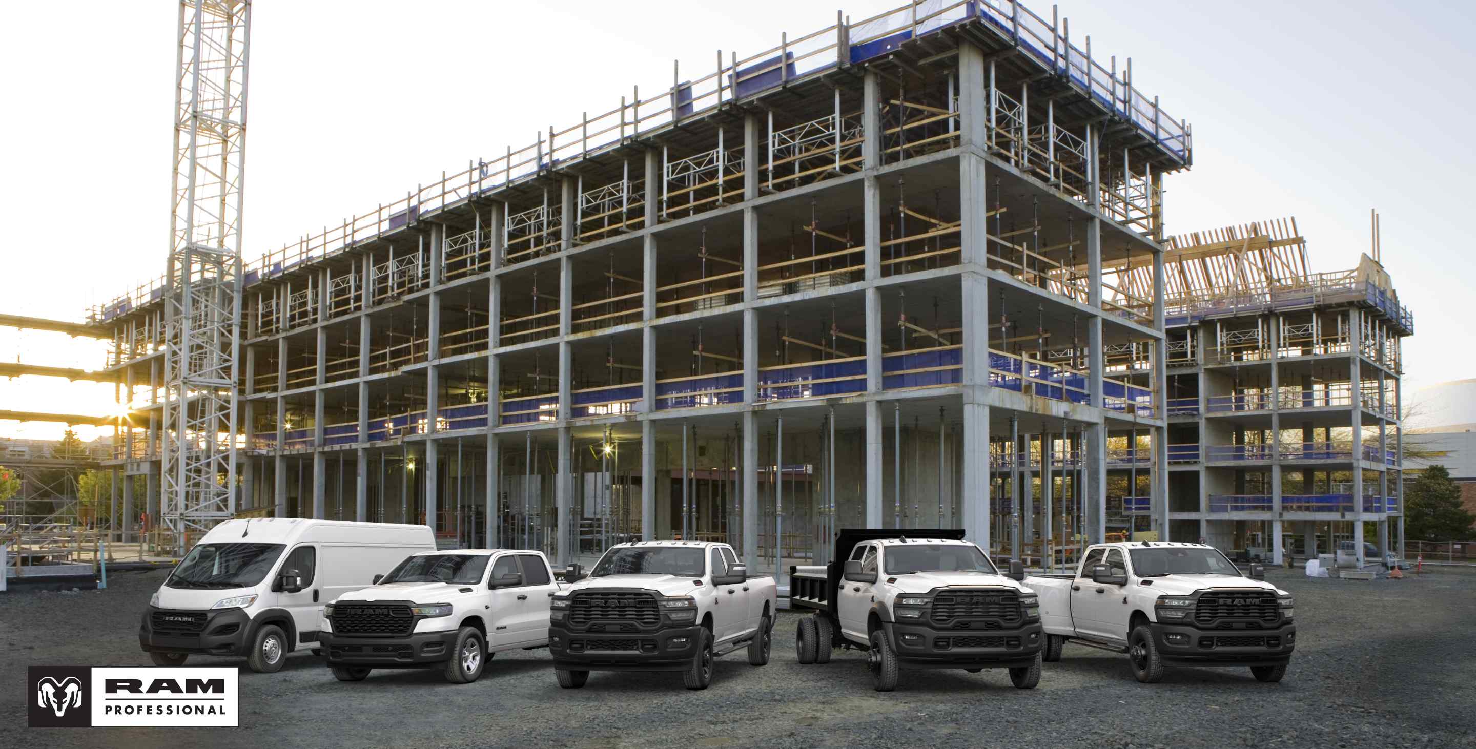 A lineup of 2026 Ram trucks and vans, all in white at a commercial construction site. From left to right: a Ram ProMaster 3500 Tradesman High Roof Cargo Van, a Ram 1500 Tradesman 4x4 Crew Cab, a Ram 2500 Tradesman 4x4 Crew Cab, a Ram 3500 Tradesman Crew Cab Chassis Cab with a dump body upfit and a Ram 3500 Tradesman 4x4 Crew Cab. Ram professional.