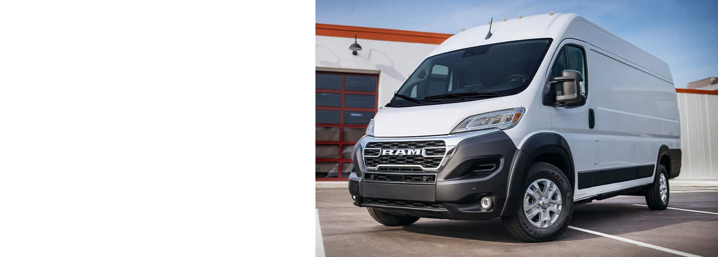 A white 2025 Ram ProMaster EV 3500 SLT High Roof Cargo Van parked near a commercial garage.