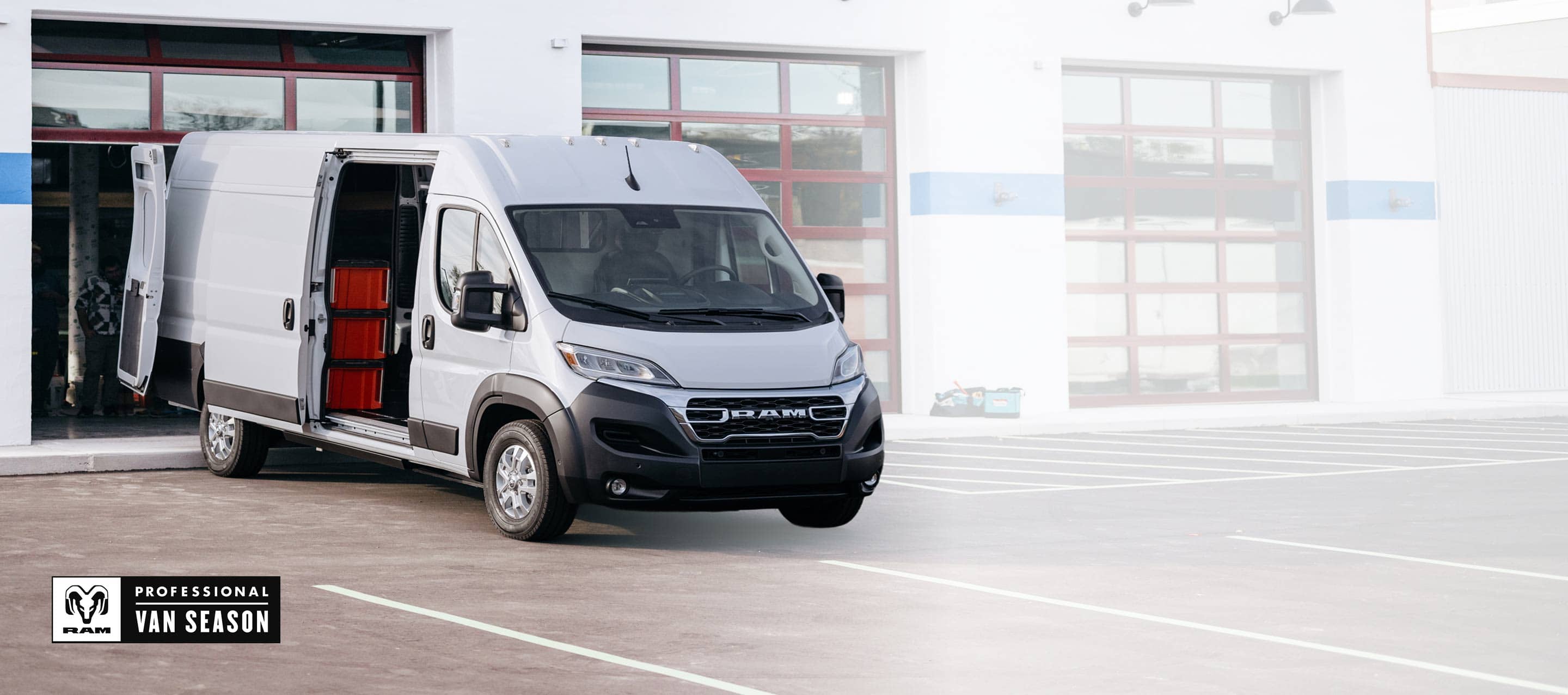 A white 2025 Ram ProMaster EV 3500 SLT Plus High Roof Cargo Van with its passenger-side sliding door and rear doors open, revealing crates on shelves. Ram Professional Van Season.
