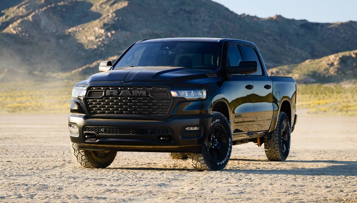 Display A black 2026 Ram 1500 Warlock 4x4 Crew Cab parked in the desert with mountains in the background.