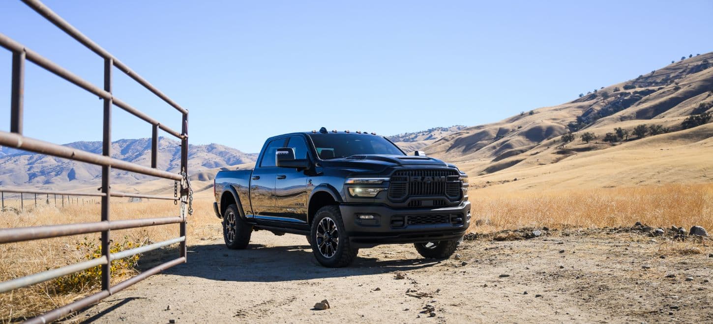 A passenger-side angle of a black 2026 Ram 2500 Rebel heavy duty pickup truck parked at a ranch in the desert