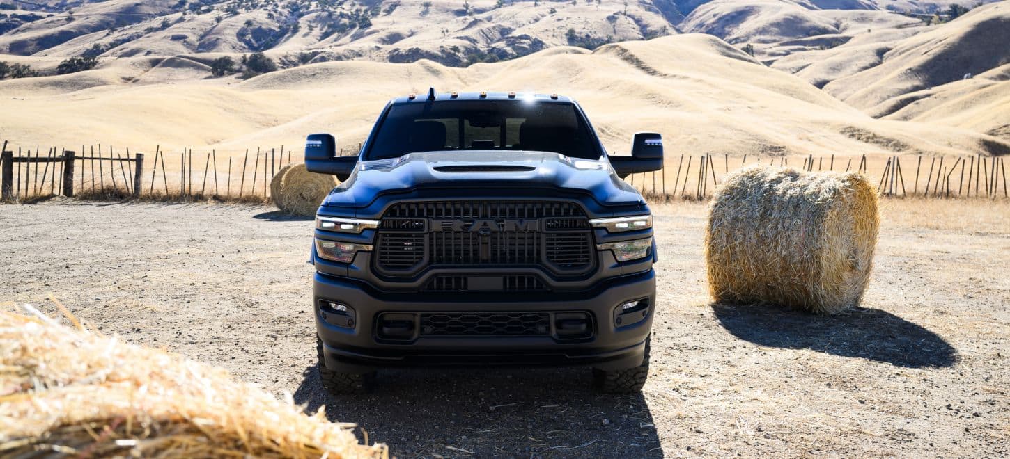 Front view of a dark 2026 Ram 2500 between hay bales on a ranch