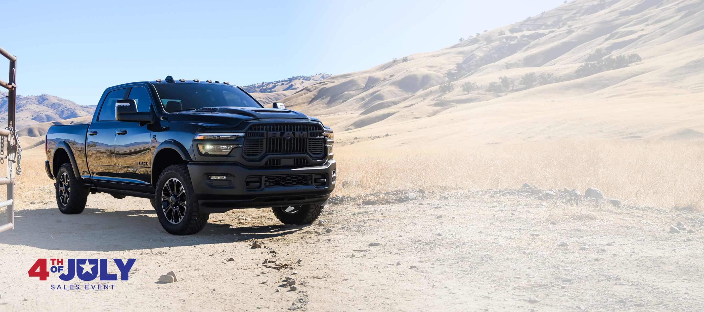 A black 2026 Ram 2500 Rebel 4x4 Crew Cab heavy-duty pickup parked at a desert ranch. 4th of July Sales event.