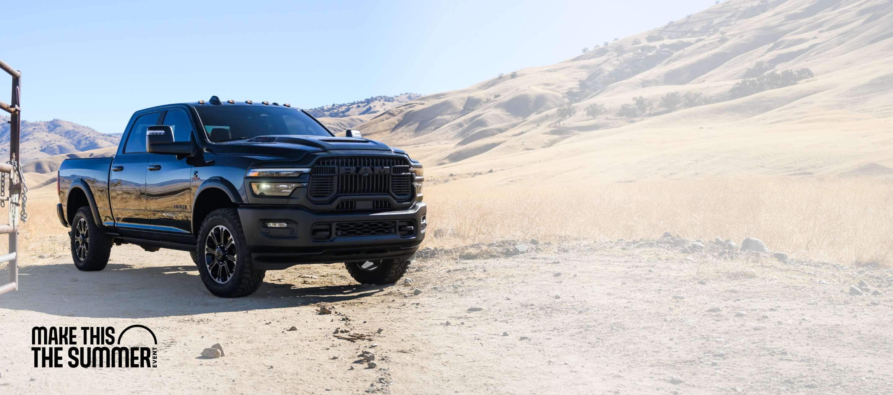 A black 2026 Ram 2500 Rebel 4x4 Crew Cab heavy-duty pickup parked at a desert ranch. Make This The Summer Event.